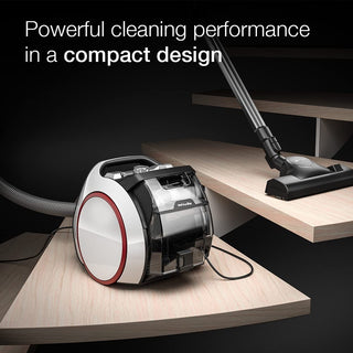 The 2-Miele Boost CX1 Pure Suction, a compact bagless canister vacuum, is shown on light wood steps with the text “Powerful cleaning performance in a compact design.” It features advanced Vortex technology for exceptional suction.