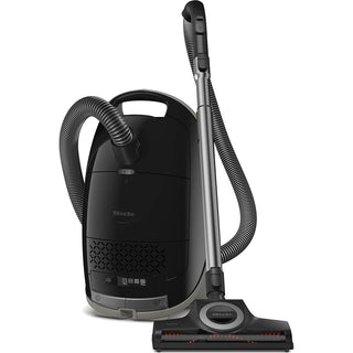 2-Miele Miele Guard M1 Cat & Dog bagged canister vacuum cleaner in black, featuring a flexible hose, handle, and floor head attachment; engineered for efficient pet hair removal and equipped with an Active AirClean filter. The product is displayed upright against a white background.