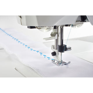 The Husqvarna Viking Opal 690Q sewing machine by Husqvarna Viking stitches a decorative blue design onto white fabric, exemplifying modern sewing innovation.