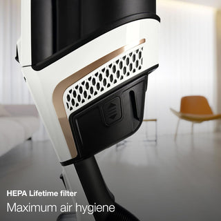 Close-up of Miele TriFlex Lotus White's HEPA Lifetime Filter with "HEPA Lifetime filter Maximum air hygiene" text, set against a modern living room background, showcasing Sew & Vac's Digital Efficiency Motor for powerful cleaning.