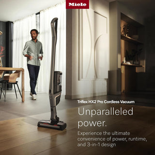 A man walks through a modern living room with the 2-Miele Triflex HX2 Pro 3-in-1 Cordless Stick Vacuum on the floor; text emphasizes its powerful performance, long-lasting runtime, versatile 3-in-1 design, and HEPA Lifetime Filter for exceptional air quality.