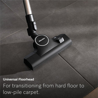 The Miele Guard L1 Cat & Dog floorhead, shown on a gray tiled floor, is described as a universal accessory for Miele canister vacuum models—making transitions from hard floors to low-pile carpet seamless and providing powerful pet hair removal.