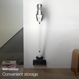 The Miele TriFlex Lotus White cordless vacuum cleaner by Sew & Vac, featuring a Triflex 3in1 design, is mounted vertically on a wall bracket in a minimalistic room.