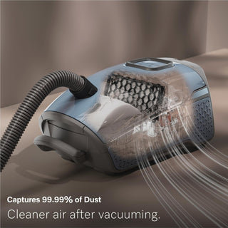 The 2-Miele Guard L1 Electro bagged canister vacuum is shown capturing airflow and dust particles, highlighting its advanced AirClean Filter. Text reads: “Captures 99.99% of Dust. Cleaner air after vacuuming.”.