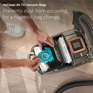 A person inserts a blue vacuum bag into an open 2-Miele Miele Guard L1 AllFloor vacuum cleaner, with text promoting HyClean Air TU Vacuum Bags featuring AirClean Plus filtration for hygienic, dust-free bag changes.