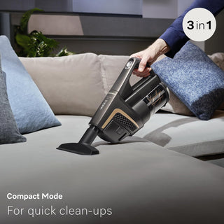 A person uses the Miele Triflex HX2 Pro 3-in-1 Cordless Stick Vacuum by 2-Miele, featuring a HEPA Lifetime Filter, to clean a light gray sofa with blue and gray pillows. Text on the image highlights “3 in 1” and “Compact Mode for quick clean-ups.”.