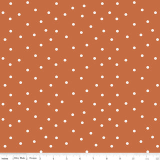 Even white polka dots on a rust pumpkin background from Riley Blake Sunflower Whispers by Lisa Audit Fabric C16673-PUMPKIN, with an inch ruler visible at the bottom. Brand: Fabric by Riley Blake.