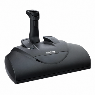 The 2-Miele SEB 228 Electro Plus Floorhead, featuring a handle and top-mounted control switches, is shown in black against a white background.