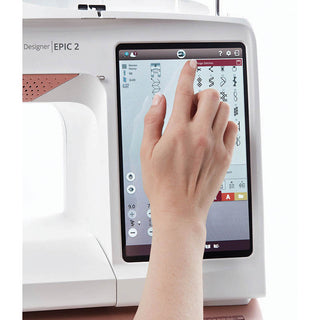 A person using a Husqvarna Viking sewing machine with a touch screen, specifically the Husqvarna Designer Epic 2.
