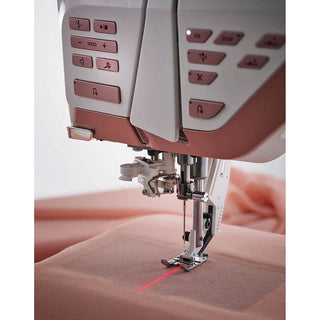 A Husqvarna Viking sewing machine, the Designer Epic 2, is being used to sew a piece of fabric.