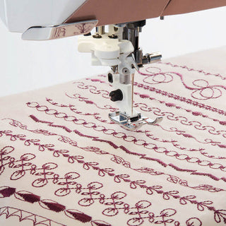 A Husqvarna Viking sewing machine with embroidery on a piece of fabric.