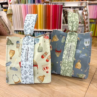 Showcased: "THE GIVING BAG" reusable gift bags, ideal for beginners, featured in the Layton In-Store Class with Carla on 12/6/25 from 1-4 PM—perfect for a sewing class or project among vibrant fabric bolts.