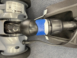Close-up of a Sew & Vac Oreck Magnesium LW1500RS (Certified Refurbished) floor cleaning machine with blue handle grip, black hose, gray wheels, and new brushroll on carpeted surface.