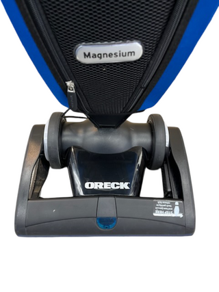 Close-up of the base and lower front of an Oreck Magnesium LW100 vacuum cleaner by Imagine Sewing & Vacuum, featuring a new brushroll, set against a white background.