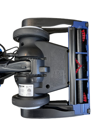 Bottom view of the Oreck Magnesium LW100 by Imagine Sewing & Vacuum, showing the brush roller, wheels, and product label on a white background.