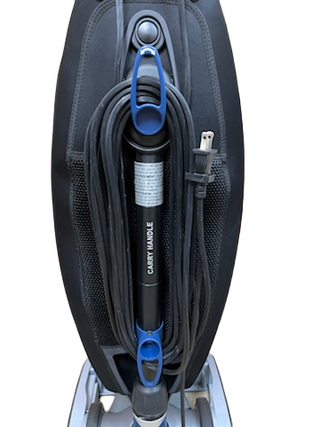 The Oreck Magnesium by Imagine Sewing & Vacuum is a reliable refurbished vacuum with a coiled black power cord wrapped around handle hooks labeled "CARRY HANDLE.