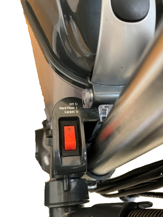 Close-up of a selector switch with Off, Hard Floor, and Carpet settings beside a red power button on the refurbished Shark Professional Navigator Lift-Away UV550 Upright Vacuum from Imagine Sewing & Vacuum.
