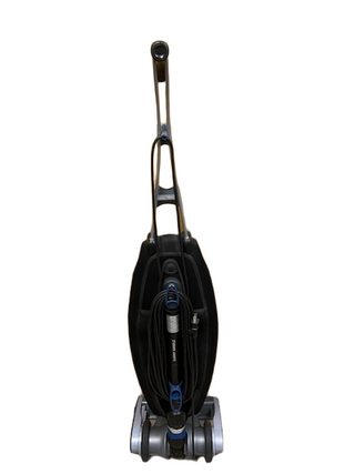 The refurbished Oreck Magnesium vacuum by Imagine Sewing & Vacuum has a black and gray body, new brushroll, and shows its cord wrapped around handle hooks in the front view.