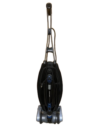 A refurbished Oreck Magnesium upright vacuum from Imagine Sewing & Vacuum is displayed on a white background, shown from the front with its power cord neatly wrapped around the hooks.