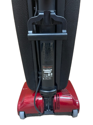 A close-up of the back of the Riccar R10P red lightweight vacuum cleaner by Imagine Sewing & Vacuum, featuring its handle and a label on the main body.