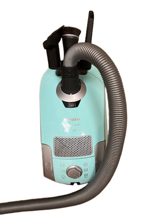A teal refurbished Miele Neptune canister vacuum from Imagine Sewing & Vacuum, featuring an attached hose and cleaning tool accessories, is set against a white background.