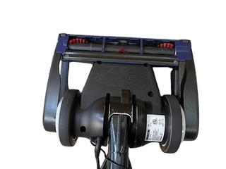Bottom view of the Imagine Sewing & Vacuum Oreck Magnesium LW100 refurbished vacuum head showing rollers, wheels, and a technical label—featuring the innovative never ending belt for lasting performance.