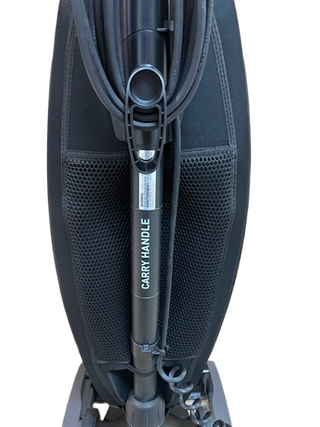 Close-up of the Oreck Discover’s back from Imagine Sewing & Vacuum, featuring a mesh pocket and a central tube marked “CARRY HANDLE.” This lightweight refurbished vacuum is built for easy portability.