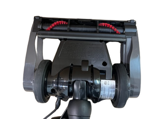 Bottom view of the Oreck Discover vacuum head by Imagine Sewing & Vacuum, featuring two large wheels, a brush roller with red bristles, and a manufacturer's label.