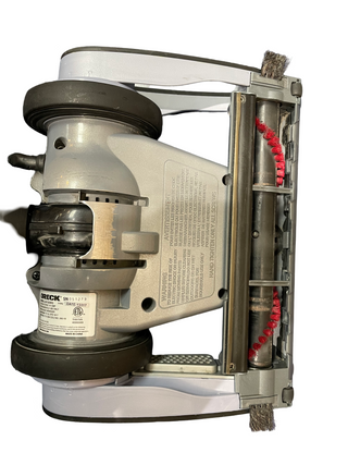 Bottom view of the Sew & Vac Oreck Magnesium vacuum showcasing the brush roll, wheels, and caution labels; ideal for hard floors and certified refurbished for reliability.