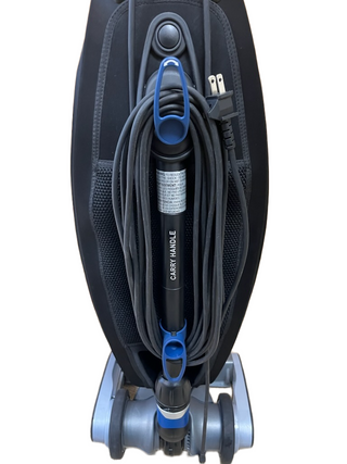 An Oreck Magnesium vacuum cleaner from Imagine Sewing & Vacuum is shown from the back, with its power cord neatly wrapped around blue hooks and the plug secured near the handle.