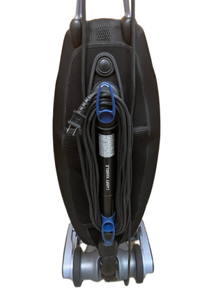 Refurbished Oreck Magnesium vacuum cleaner by Imagine Sewing & Vacuum, shown upright with black and gray design, blue accents, and a coiled cord viewed from the back against a white background; combines powerful cleaning performance with a sleek look.
