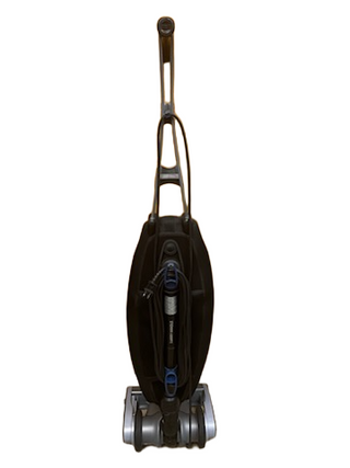 A reconditioned Oreck Magnesium upright vacuum cleaner by Imagine Sewing & Vacuum, featuring a visible handle, cord wrapped around hooks, and wheels at the base.