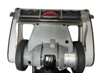 Underside of a refurbished Oreck Magnesium vacuum cleaner head showing the brush roll, wheels, and warning labels.