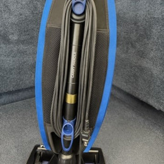 A close-up of the 1-Oreck LW100 Magnesium Lightweight Vacuum CR (Certified Refurbished) with its cord wrapped around the handle on carpet—features advanced HEPA filtration for cleaner air.