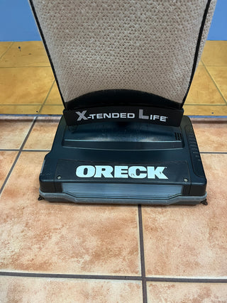A Sew & Vac Oreck XL21 extended life upright vacuum cleaner with a new belt on a tiled floor, positioned at the base of a carpeted cleaning ramp.