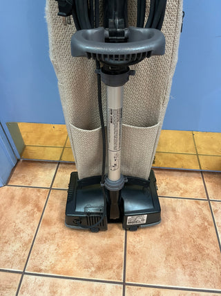 Oreck XL21 upright vacuum cleaner with a new bag standing against a beige towel on a tiled floor in front of a blue wall. (Brand Name: Sew & Vac)
