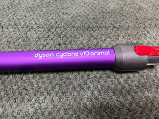 Certified refurbished purple Sew & Vac Dyson Cyclone V10 Animal cordless vacuum cleaner handle on a carpeted floor.