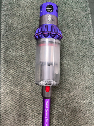 A Sew & Vac Dyson Cyclone v10 Animal certified refurbished vacuum cleaner with a purple and silver color scheme, displayed on a gray carpet.