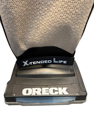 Close-up of the base of an Oreck XL21 vacuum cleaner from Imagine Sewing & Vacuum, featuring "X-Tended Life" and "ORECK" on the front.