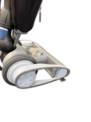 Close-up of the lower part of the Oreck Magnesium LW1500 refurbished vacuum by Imagine Sewing & Vacuum, showing its wheel, new brushroll, and part of the dust container on a white background.