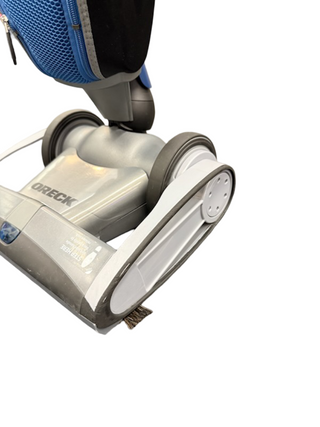 Close-up view of the base and wheels of the Oreck Magnesium upright vacuum by Imagine Sewing & Vacuum against a white background, ideal for hard floors.