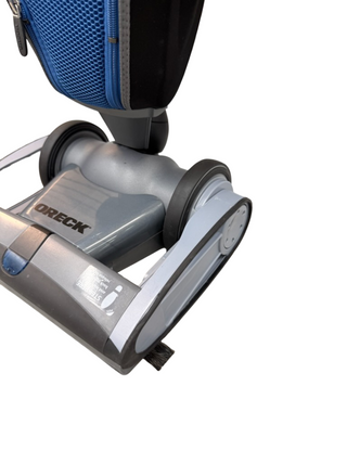 Close-up of the base of the Oreck Magnesium vacuum by Imagine Sewing & Vacuum, featuring a blue fabric bag and photographed on a white background.