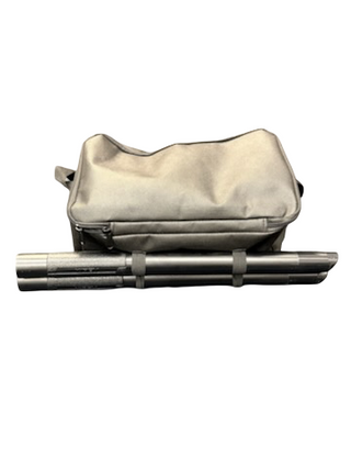 A tan fabric bag with a zipper sits behind a strapped, cylindrical metallic object—a Kirby Altair Platinum vacuum from Imagine Sewing & Vacuum, renowned for premium cleaning performance.