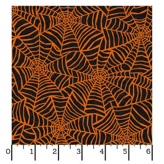 Maywood Studios Pumpkin Grove SPIDER WEBS BLACK/ORANGE MAS11183-JO fabric yardage by 47-EE Schenck, featuring a black fabric with an orange spiderweb pattern, is shown next to a ruler marked from 0 to 6 inches for scale. This charming fabric is available by the yard and qualifies for free shipping.