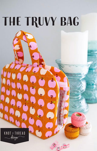 Orange and pink apple-patterned Truvy Bag shown with candles and thread spools; ideal as a sewing organizer. Text: "Truvy Bag Class with Carla 10/25/25 1-5 pm" and "Layton In-Store Class.