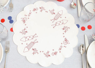The Kimberbell Patriotic Parade One-Day Event by Layton In-Store Class features a white scalloped table round with red embroidered rockets and florals, set with festive decor—perfect for your May 9, 2026 celebration.