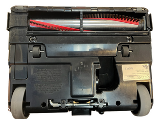 The underside of the Imagine Sewing & Vacuum Riccar R10P lightweight vacuum cleaner head displays a rotating brush with red bristles, two wheels, and various mechanical components.