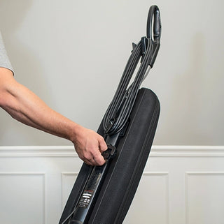A man is holding a Riccar R10S Lightweight Supralite Standard vacuum cleaner in a black HEPA media bag.