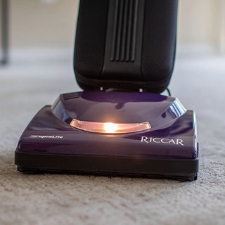 A multi-floor cleaning, purple Riccar R10S Lightweight Supralite Standard vacuum cleaner with a HEPA media bag sitting on the floor.