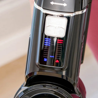 Close-up of a black Riccar R65 Cordless Stick Vacuum's control panel, featuring red and blue LED indicators and arrow buttons. With SupraCyclonic™ filtration, it delivers optimal performance for spotless cleaning.